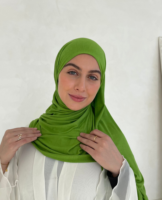 A muslim woman wearing a green jersey hijab, smiling with full coverage hijab style.