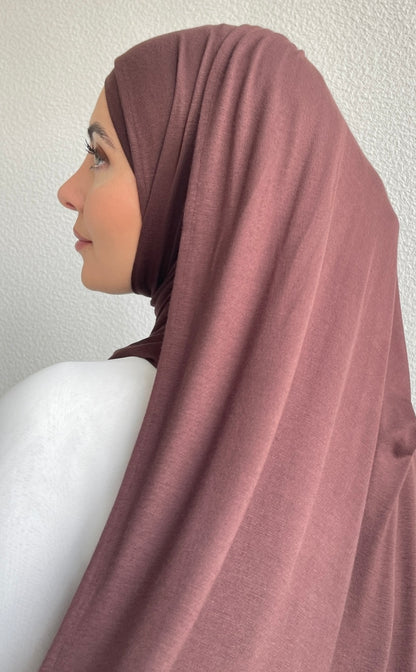 A muslim hijabi woman wearing a brown hijab over a modest attire. 