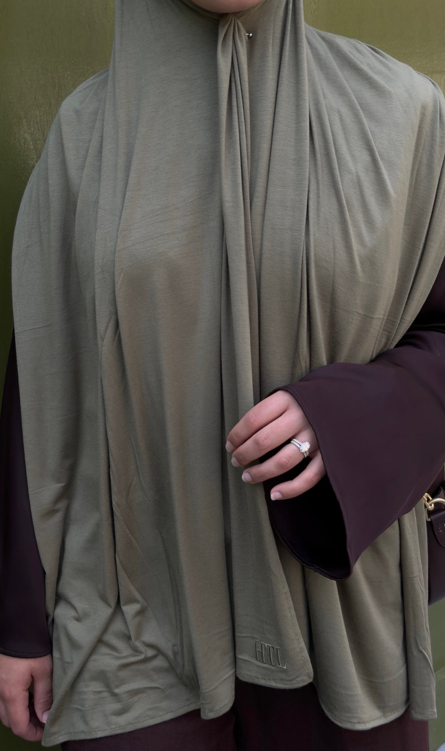 Person wearing a beige hijab with a dark sleeve visible brown and green combo for hijabis