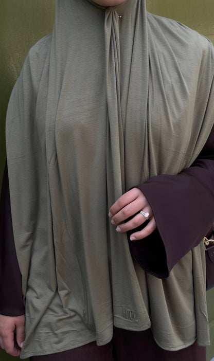 Person wearing a beige hijab with a dark sleeve visible brown and green combo for hijabis
